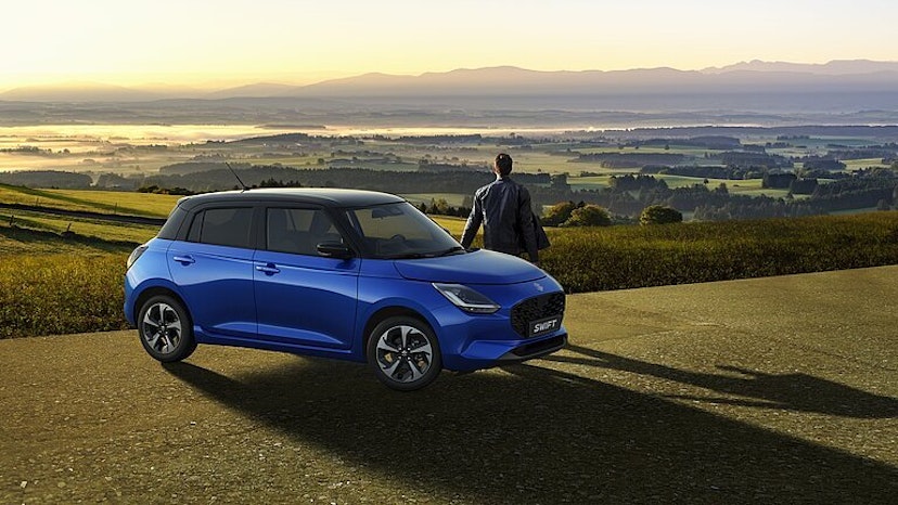 Blauer Suzuki Swuft mit Mann, im Hintergrund schöne Landschaft