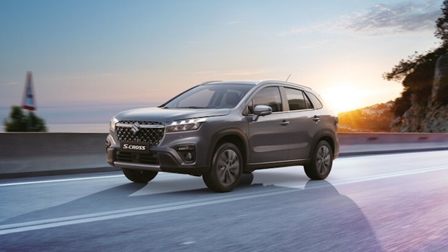 Una S-Cross grigia percorre la strada all'alba.