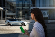 Zeekr im Hintergrund, Frau mit Handy im Vodergrund