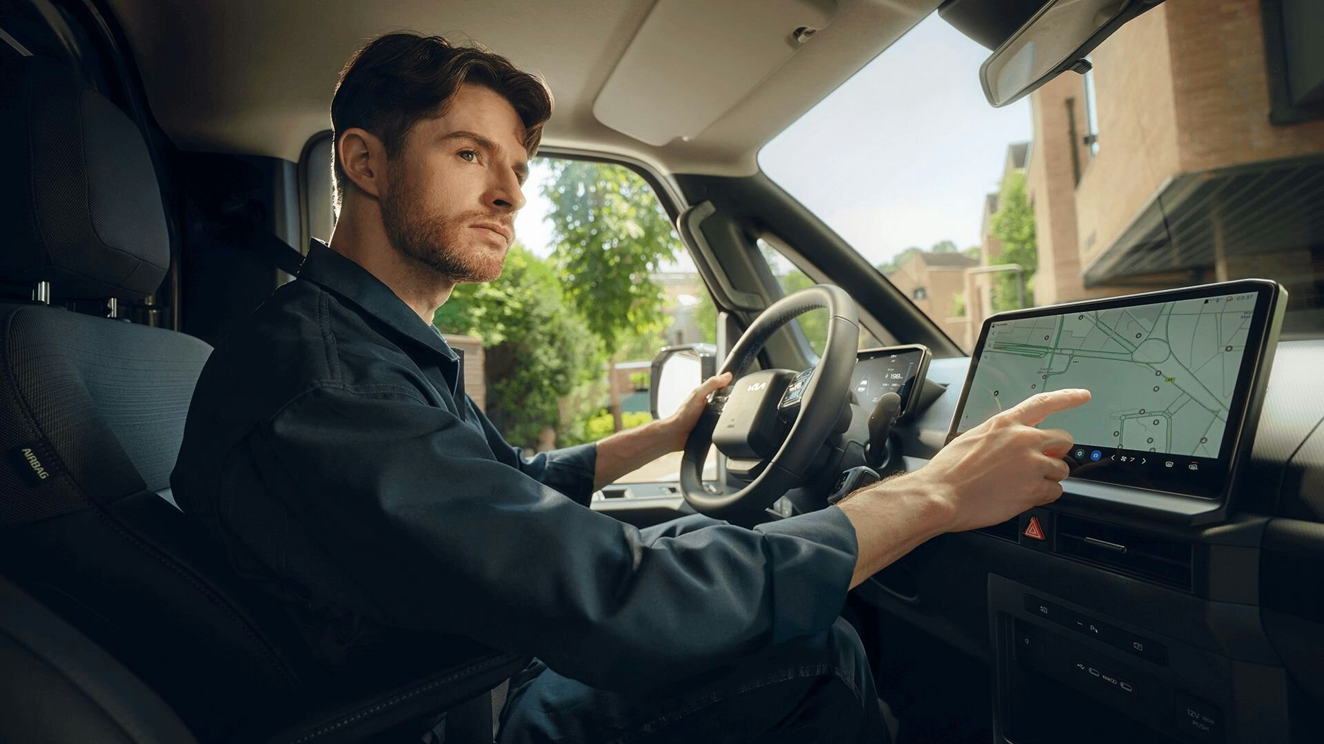 Frontansicht des Kia PV5 Passenger, parkiert in einer modernen Wohngegend, wobei das klare und geometrische Aussendesign hervorgehoben wird