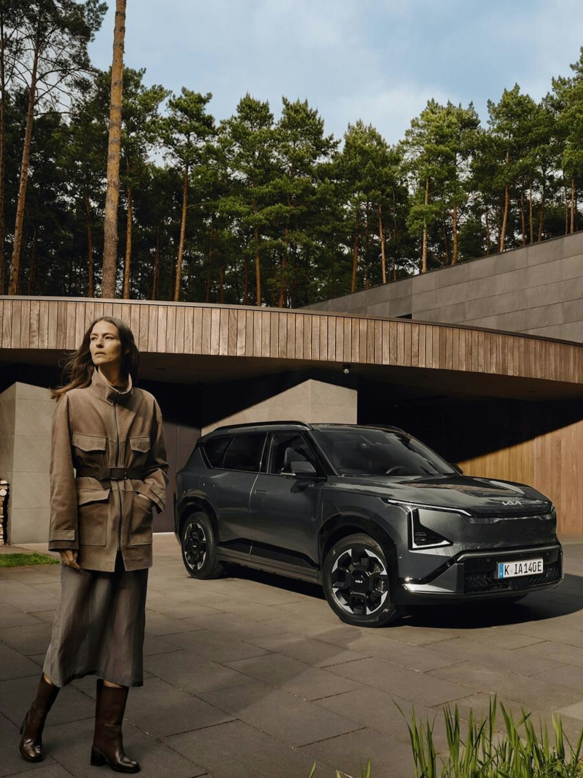 Eine Frau steht neben dem Kia EV5 im Wald