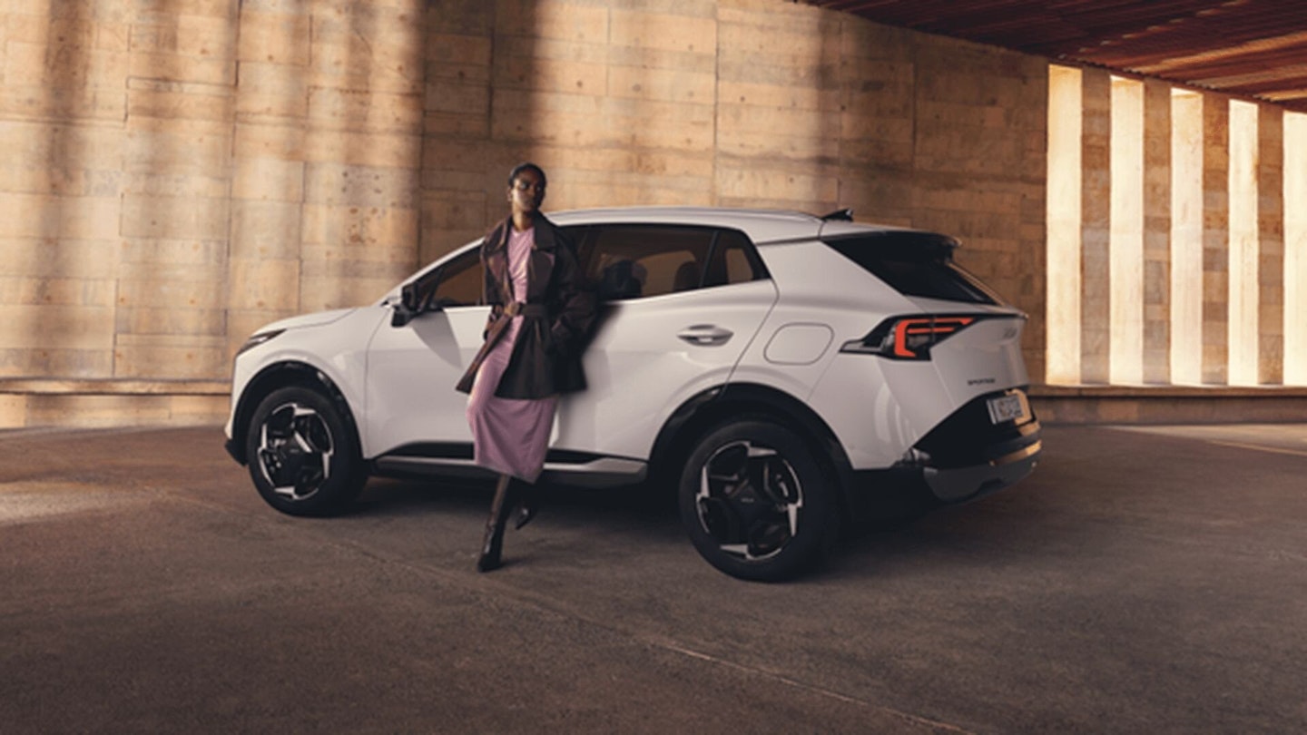 Una donna si appoggia alla nuova Kia Sportage