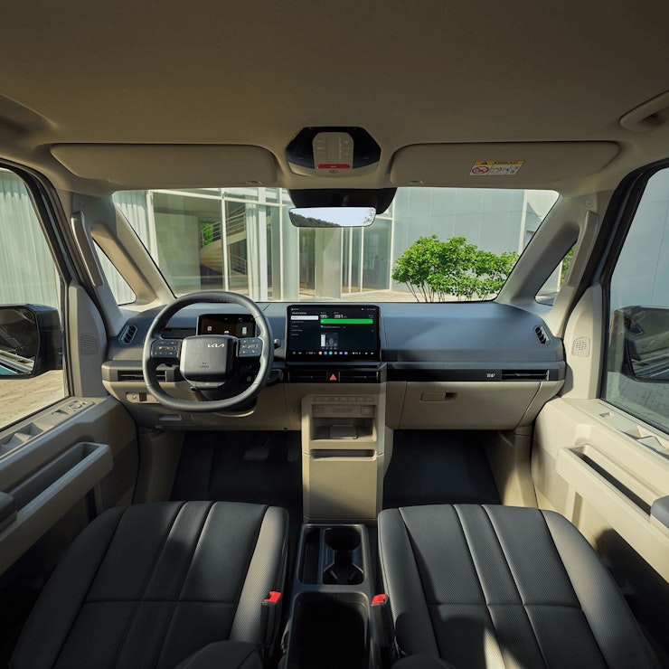 Innenansicht vorne des Kia PV5 Passenger mit breiter Windschutzscheibe, beheizbarem Lenkrad und strapazierfähigen Sitzbezügen für den täglichen Gebrauch