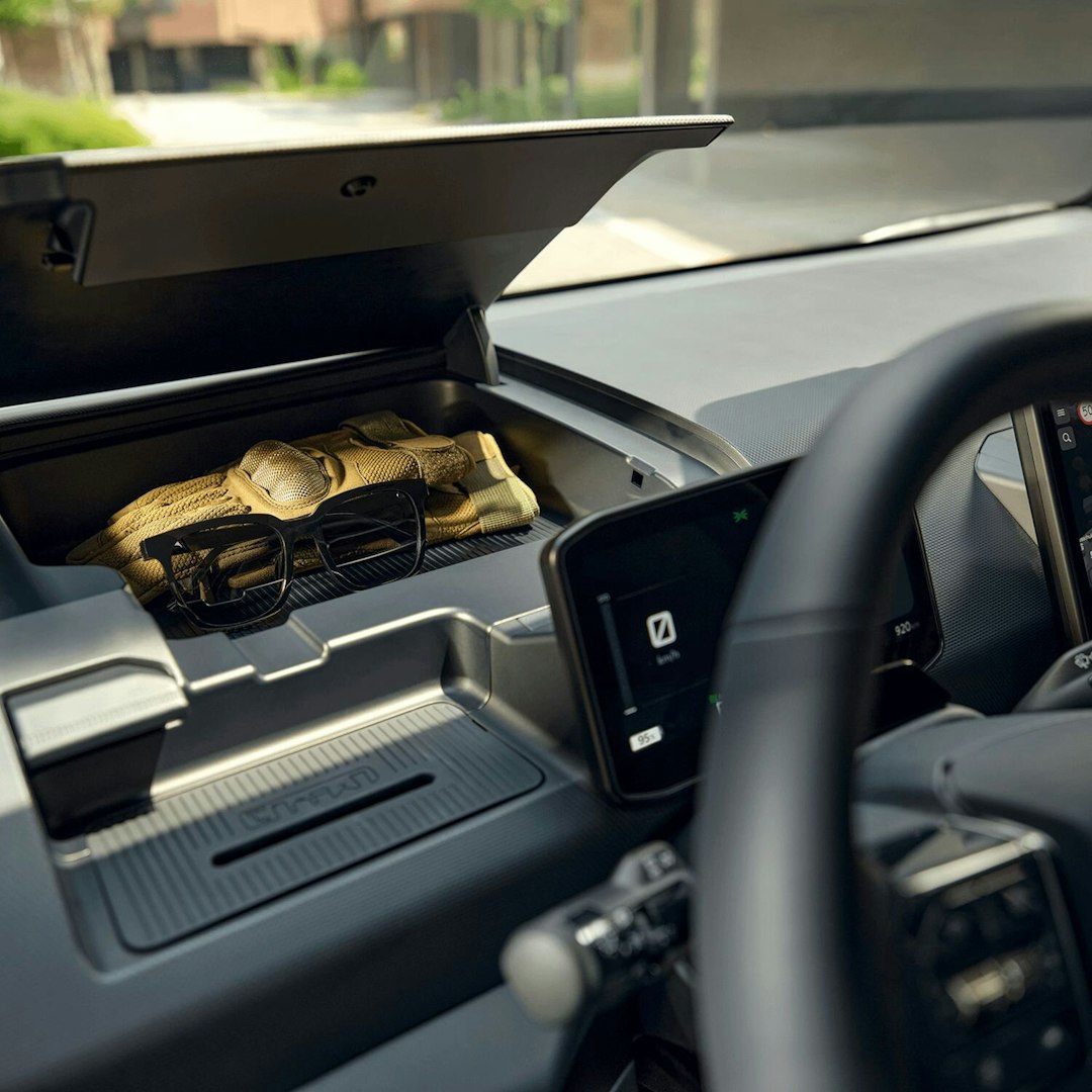 Innenansicht vorne des Kia PV5 Passenger mit mehreren versteckten Staufächern im Fahrer- und Beifahrerbereich