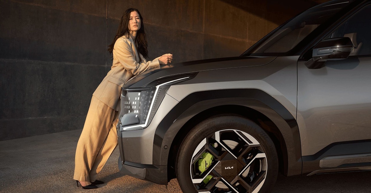 Eine Frau lehnt sich an den Kia EV9 GT