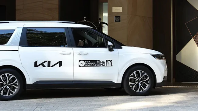 Kia Carnival als offizielles Fahrzeug der FIFA-Weltmeisterschaft vor einem Hoteleingang