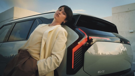 Eine Frau lehnt seitlich am Kia EV3