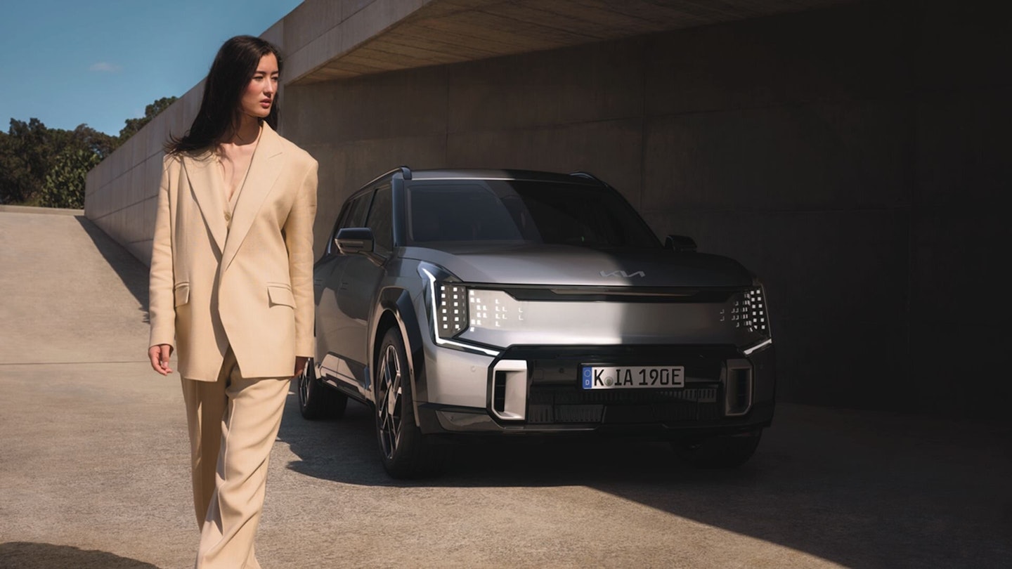 Eine Frau bewegt sich vom Kia EV9 GT weg
