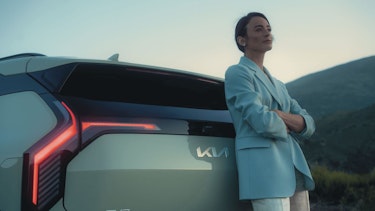 Eine Frau lehnt sich an das Heck des Kia EV3