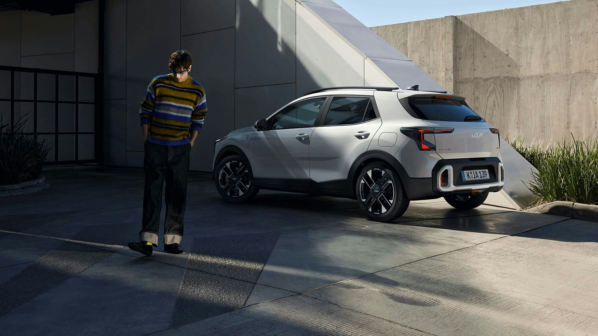 Ein Mann mit buntem Pullover entfernt sich vom parkierten Kia Stonic