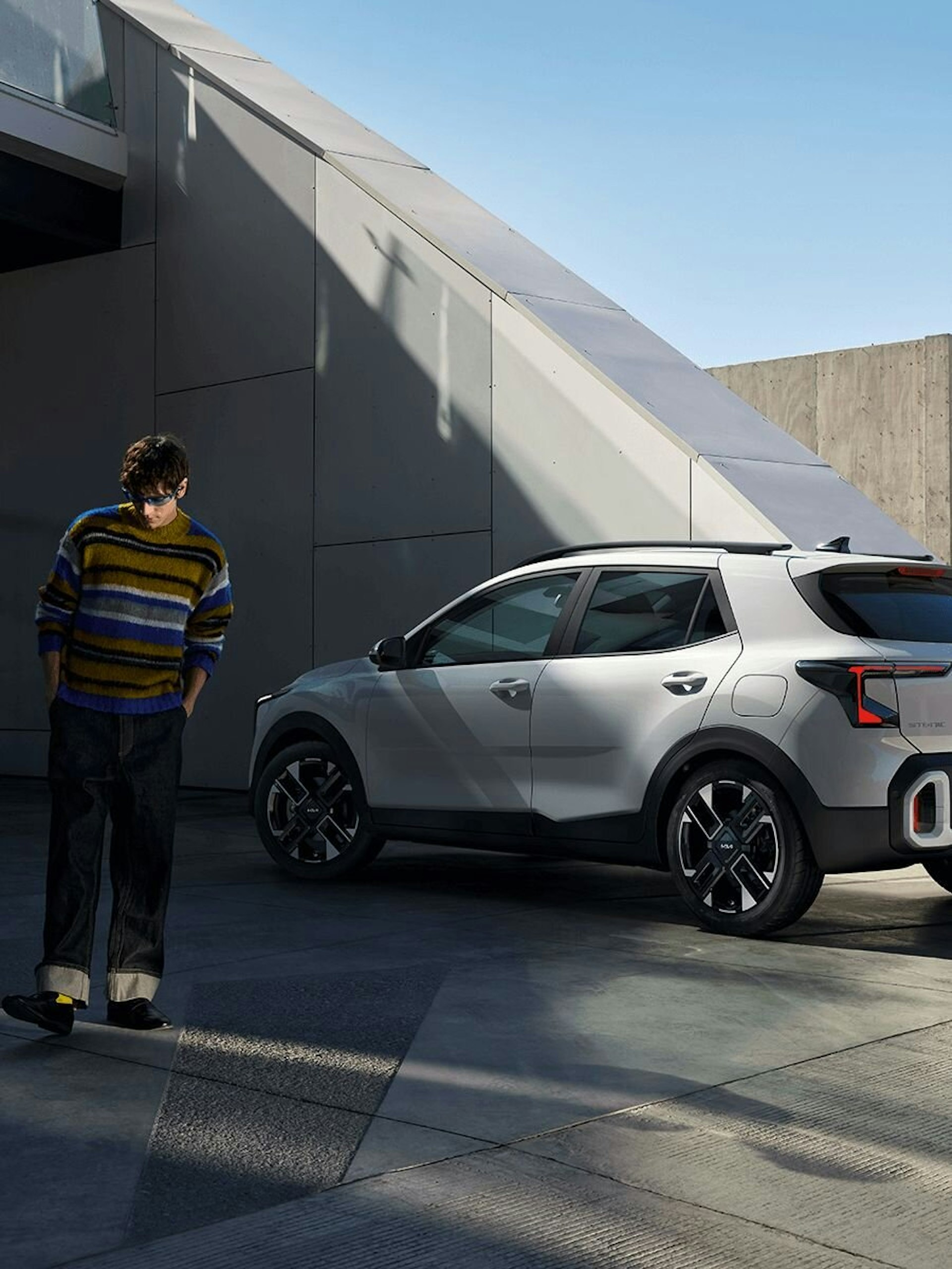 Ein Mann mit buntem Pullover entfernt sich vom parkierten Kia Stonic