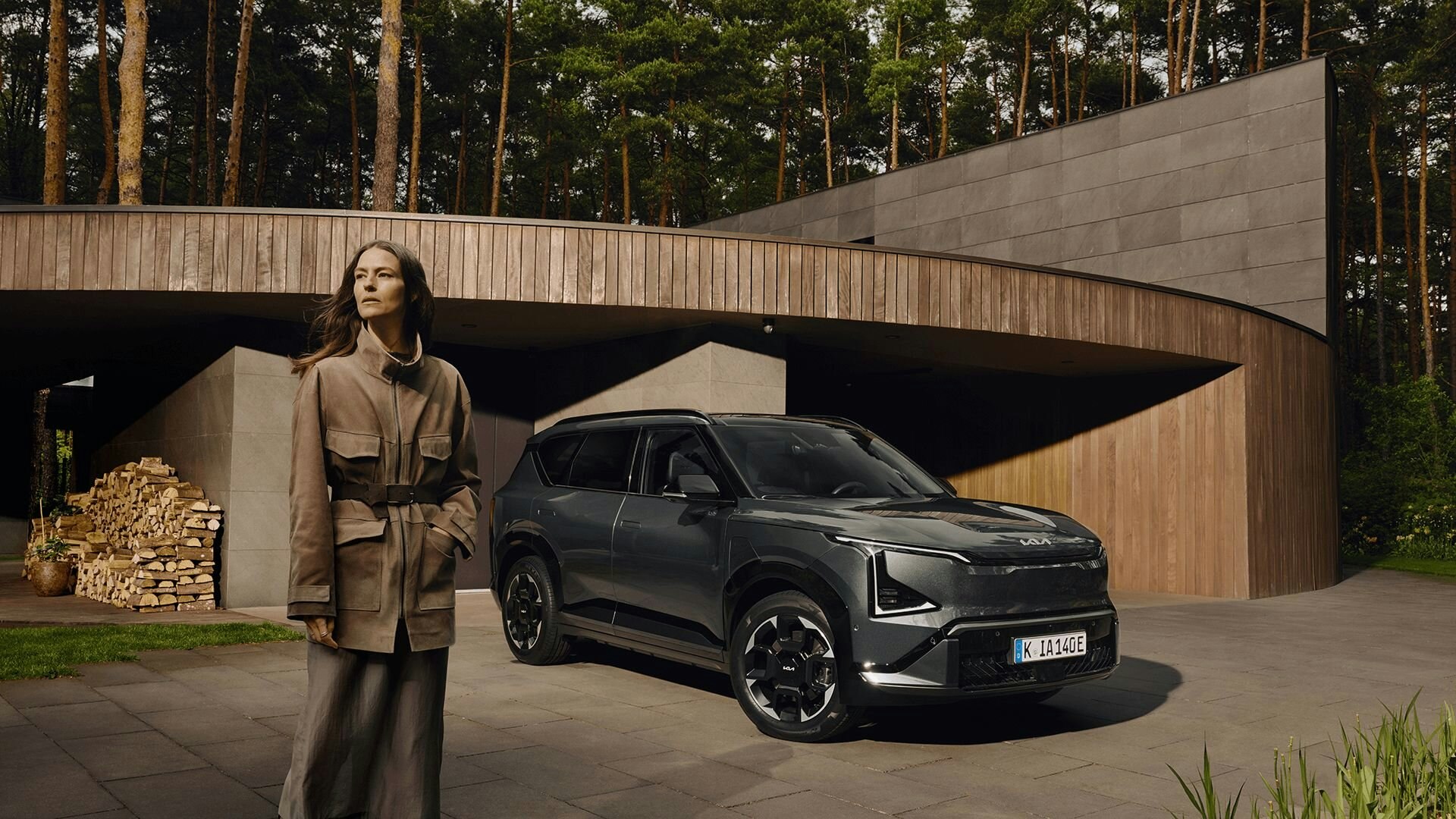 Eine Frau steht neben dem Kia EV5 im Wald