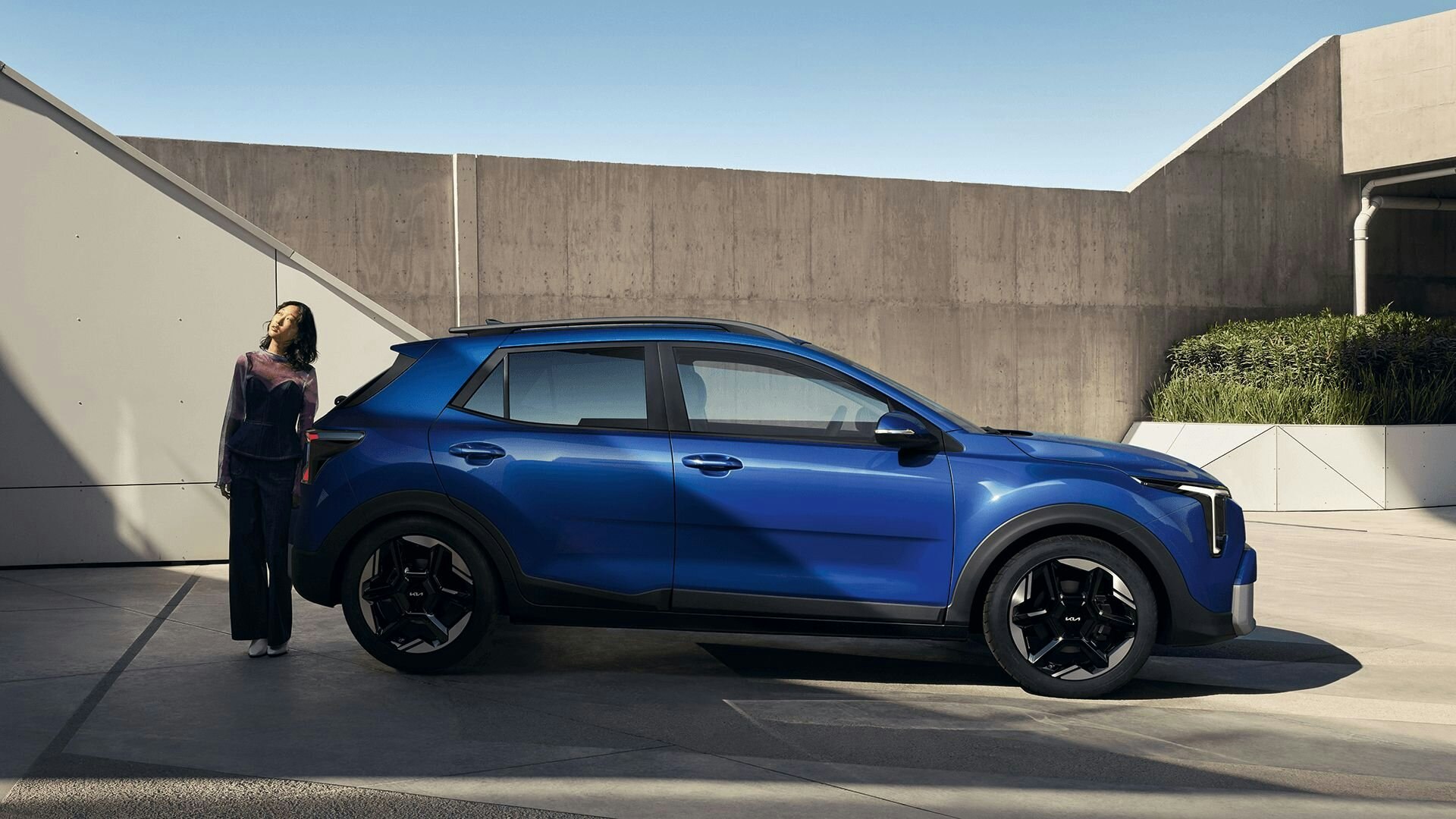 Eine Frau steht hinter dem neuen Kia Stonic und schaut in den Himmel