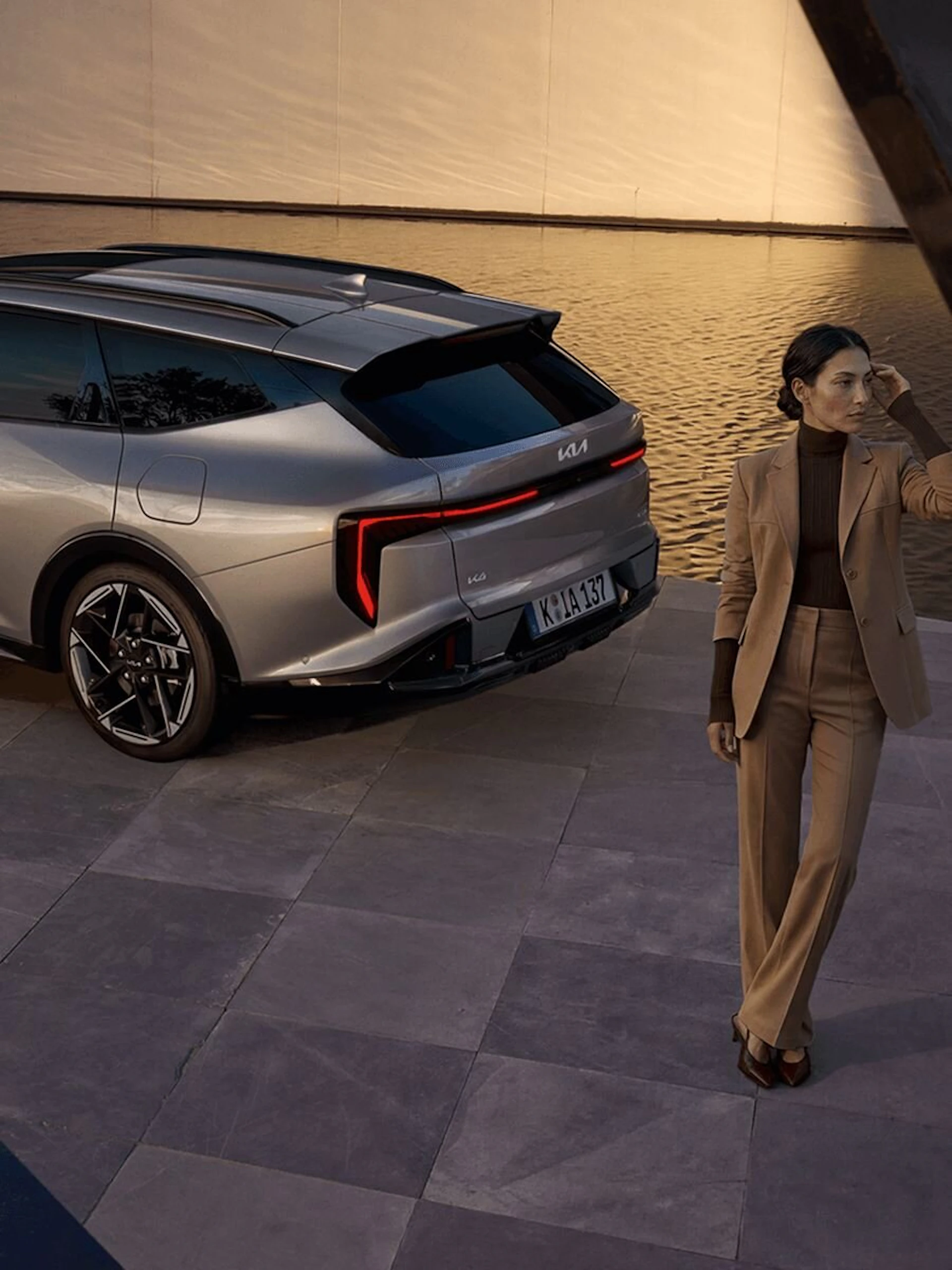 Eine Frau steht hinter dem Kia K4 Sportswagon